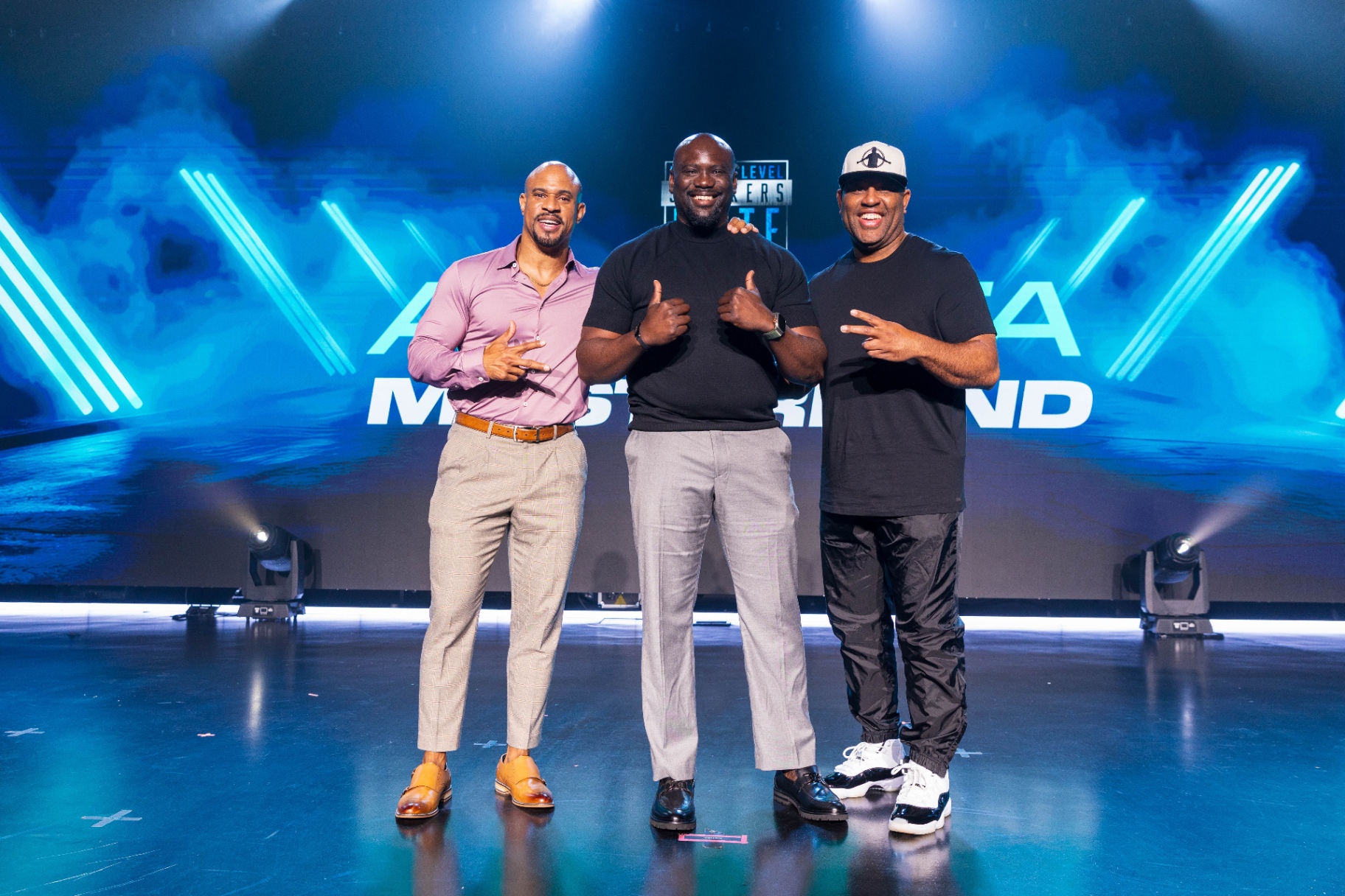Brown Charité on stage with two fellow speakers at a mastermind event